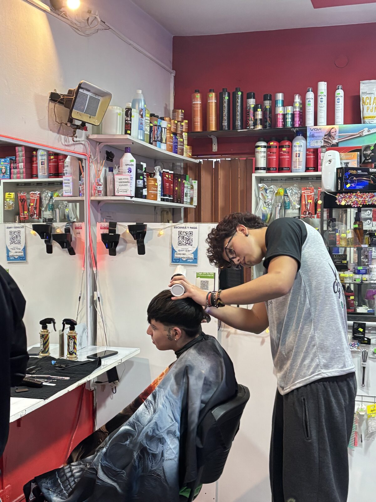 Alumno realizando un corte de cabello a un modelo